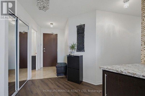Living room with a large L-shaped sofa, television, wooden cabinet, and a view into the kitchen. - Ph211 - 7250 Yonge Street, Vaughan