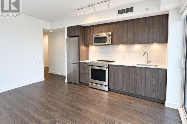 Interior view of a kitchenette with dark wood cabinets and appliances. - Ph2408 - 30 Samuel Wood Way, Toronto