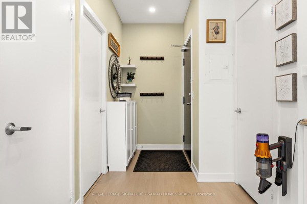 Interior hallway with white doors, light wood floors, and storage units. - Ph2612 - 225 Sackville Street, Toronto