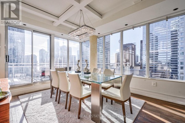 Dining area with a glass table and chairs, floor-to-ceiling windows, and a city view. - Ph2701 - 8 Colborne Street, Toronto
