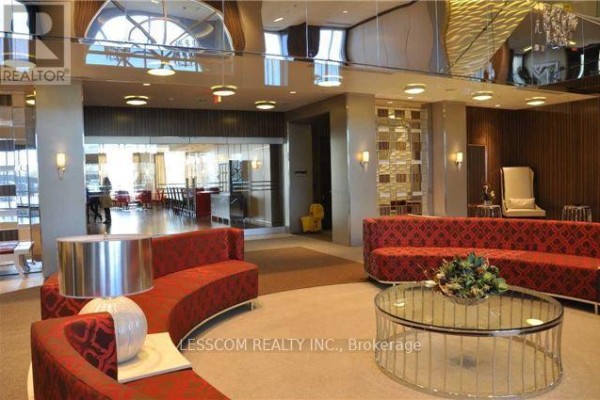 Luxurious lobby with curved red patterned sofas, glass coffee table, and mirrored ceiling. - Ph28 - 2 Eva Road, Toronto