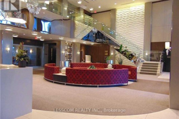 Building lobby with textured wall panels, glass staircase, and modern seating arrangements. - Ph28 - 2 Eva Road, Toronto