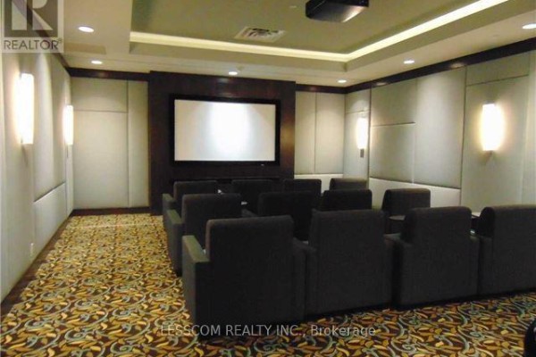 Home theater room with rows of plush chairs, large projection screen, and patterned carpet. - Ph28 - 2 Eva Road, Toronto
