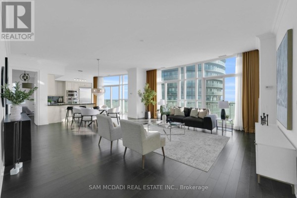 Spacious living area with large windows, dark hardwood floors, and modern furnishings. - Ph3 - 50 Absolute Avenue, Mississauga