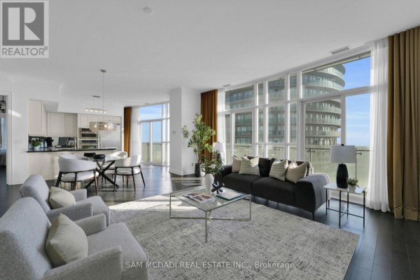 Living room showcasing a cozy seating area and expansive city views through large windows. - Ph3 - 50 Absolute Avenue, Mississauga