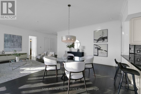 Dining area with a round table, modern chairs, and decorative artwork on the walls. - Ph3 - 50 Absolute Avenue, Mississauga