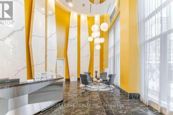 Luxurious condo lobby with high ceilings, yellow walls, marble accents, and a circular seating area. - Ph3015 - 70 Princess Street, Toronto