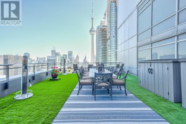 Open kitchen with stainless steel appliances, dining table, and city views. - Ph5201 - 25 Telegram Mews, Toronto