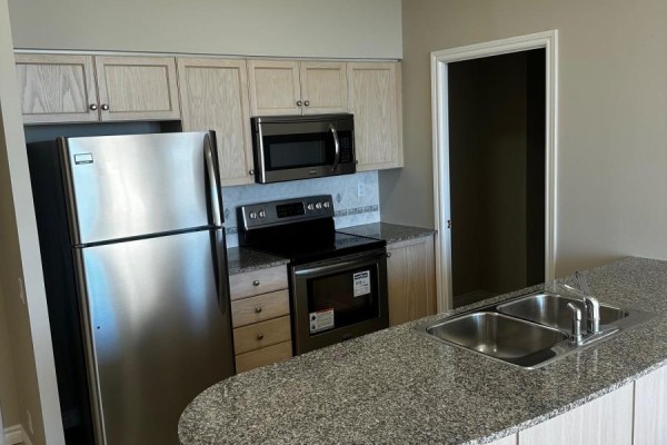 Stainless steel refrigerator, microwave, and electric range with granite countertops and light wood cabinets. - Ph7 - 1720 Eglinton Avenue E, Toronto