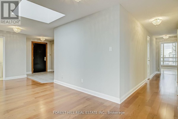Hallway view with hardwood flooring, a skylight, and a door leading outside - Ph7 - 55 Kingsbridge Garden Circle, Mississauga