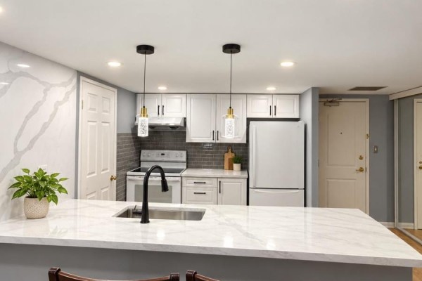 Modern kitchen with white cabinets, quartz countertops, stainless steel sink, and pendant lights. - Ph7 - 701 King Street W, Toronto