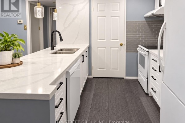 Kitchen with white appliances, grey tile backsplash, white cabinets, and dark wood flooring. - Ph7 - 701 King Street W, Toronto