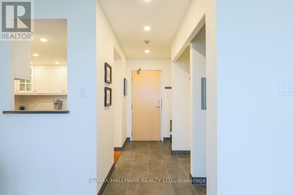 Interior hallway with tiled floor, apartment door, and a view into the kitchen. - Ph83 - 1 Greystone Walk Drive, Toronto