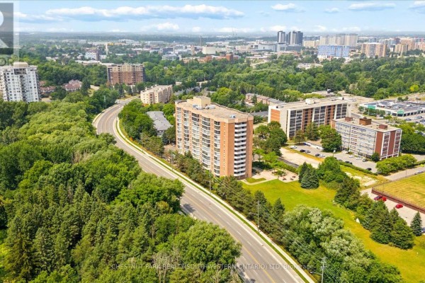 View of the apartment building and a curving road with dense green trees and development. - Ph9 - 265 Westcourt Place, Waterloo