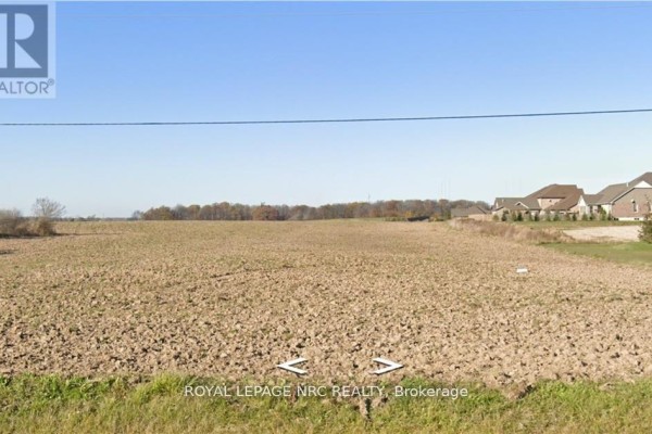 Open field view with cleared land and distant residential homes. - Pt Lot 14 Haldimand 9 Road, Haldimand