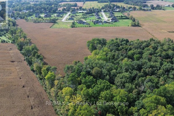 Aerial perspective of harvested fields adjacent to a forest, with distant houses visible. - Pt Lt 15, Con 1 Pt 1 & 2 Deer Crescent, Norwich