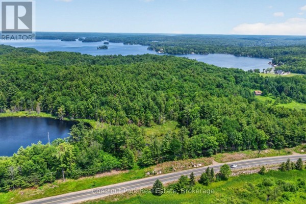 Aerial view showing a paved road, a dark lake, and a forested area in winter. - Pt Lt 33 Con 2 (pt 2) Muskoka 118 Road W, Muskoka Lakes