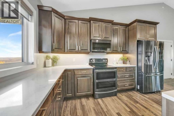 Kitchen with dark wood cabinets, white countertops, stainless steel stove, and refrigerator. - Pt Nw 8-45-1-w4, Rural Wainwright No  61, M D  Of