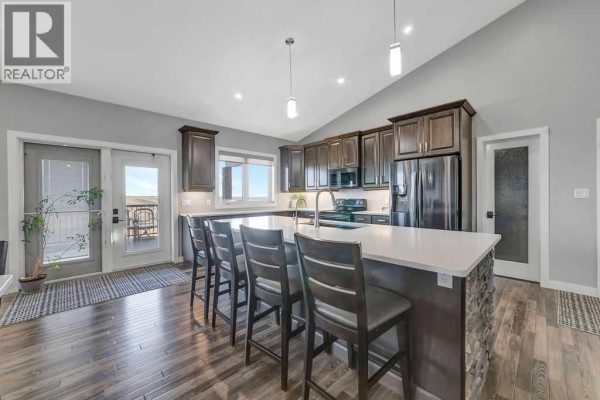 Open-concept kitchen and living area with a large island, dark cabinets, and a vaulted ceiling. - Pt Nw 8-45-1-w4, Rural Wainwright No  61, M D  Of