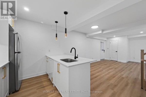 View of kitchen island, stainless steel refrigerator, and living area. - R - Garden - 221 Churchill Avenue, Toronto