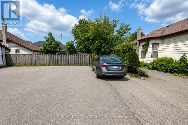 Rear exterior view of the property with a paved parking area and a car. - Rear - 220 Hamilton Road, London East
