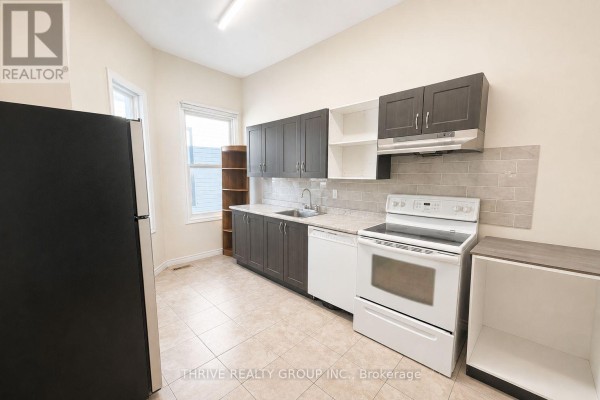 Kitchen with dark wood cabinets, tiled backsplash, and white appliances. - Rear - 220 Hamilton Road, London East