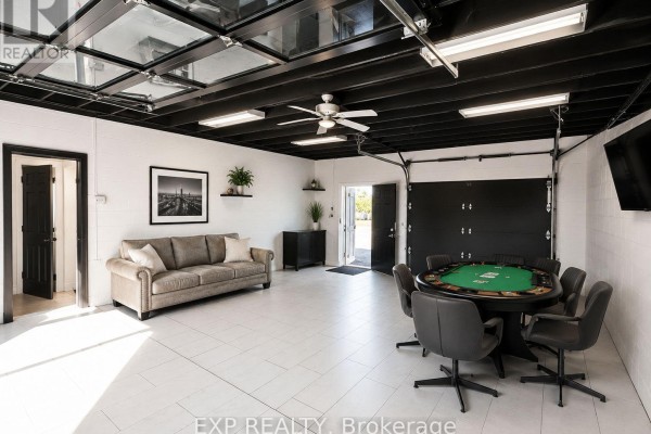 Spacious interior with a poker table, seating, sofa, and two garage doors, one glass and one solid. - Rear - 313 Horton Street, London East
