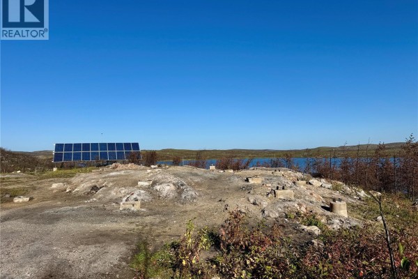 View from a boat moving through water, showing a rocky shoreline with scattered debris and vegetation. - Reynold's Bay Titled Lot, Northern Admin District
