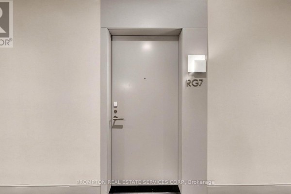A grey apartment door labeled RG7 with a modern light fixture beside it. - Rg7 - 396 Highway 7 E, Richmond Hill