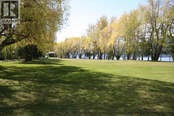 Expansive green lawn in a park setting with trees, overlooking a calm body of water. - Ridge Way Lot# 114, Windermere