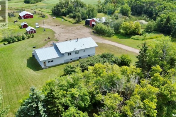Aerial view of a white farm house with a silver roof and surrounding trees, situated on a large rural property. - Rm Of Kellross Farm, Kellross Rm No  247