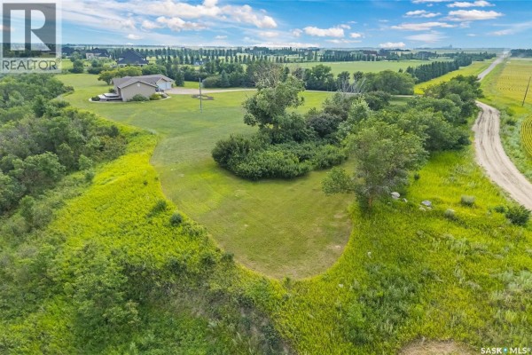 Aerial view of the acreage, featuring wooded areas, green fields, and a distant highway. - Roberts Riverfront Acreage, South Saskatchewan River