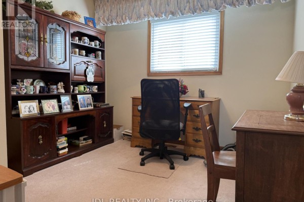 Home office with a wooden hutch filled with mugs, a desk, and a chair, overlooking a window. - Room - 28 Orangewood Crescent, Toronto