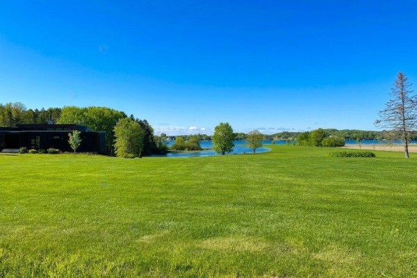 A dark modern building is visible on the left, surrounded by green fields and water. - Rue Notre-dame, Montebello