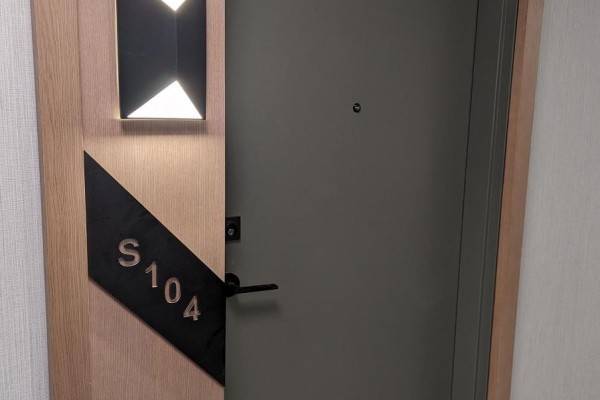 Close-up of unit S104 door with unique lighting and wood accents. - S104 - 180 Mill Street, Toronto