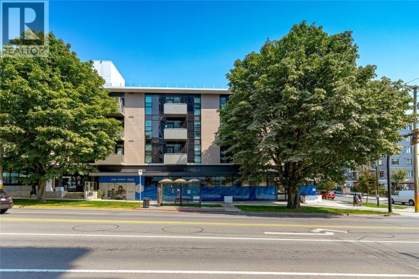 Exterior view of a modern apartment building with trees and a bus stop in front. - S404 1411 Cook St, Victoria