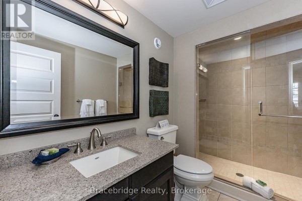 Bathroom vanity with granite countertop, sink, mirror, and glass-enclosed shower. - Sandfield 3 W3 - 3876 Muskoka Rd 118 Highway W, Muskoka Lakes