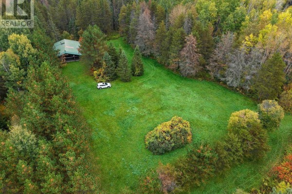 Aerial view of a log cabin nestled within a clearing surrounded by autumn foliage and evergreen trees. - Shalf Lt 6 Con 2 Day Mar Road, Englehart
