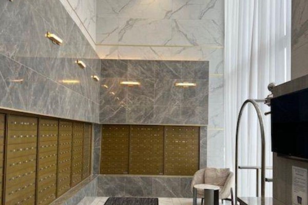 Marble-tiled lobby with brass mailboxes, a single armchair, and overhead lighting fixtures. - Shared Unit 3107 - 898 Portage Parkway, Vaughan