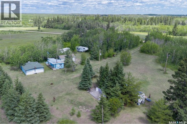 An open-air garage with a roof and concrete floor contains items and a table. - Shell Lake Private Trailer Park, Canwood Rm No  494