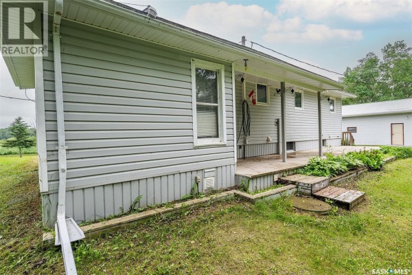 Close-up of the house exterior with vinyl siding, a covered patio, and garden beds. - Sherman, Big Quill Rm No  308