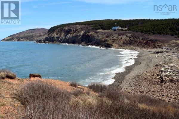 View of a sheltered cove with waves, a pebble beach, and rugged terrain. - Shore Road, Hwy#219, St Rose