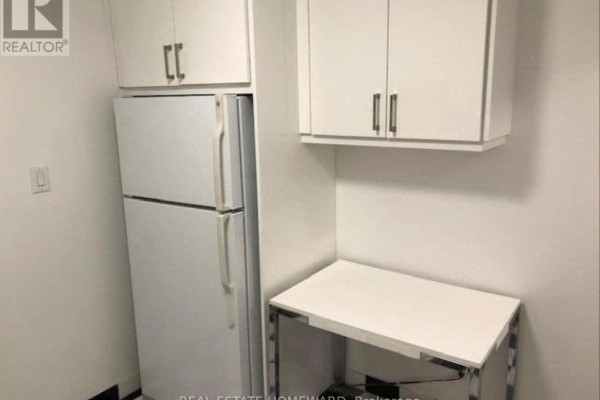 Utility area with white refrigerator, storage cabinets, and small table - Side - 274 Rumsey Road, Toronto