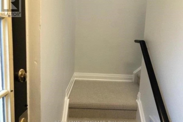 Staircase with carpeted steps leading to upper level, light gray walls, and black railing - Side - 274 Rumsey Road, Toronto