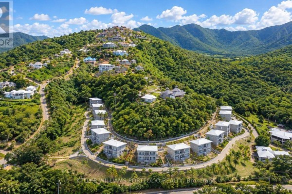 Aerial view of modern condos arranged in a curve on a tree-covered hillside. - Sky Residence - Sugar Ridge Condos Valley Road, Antigua