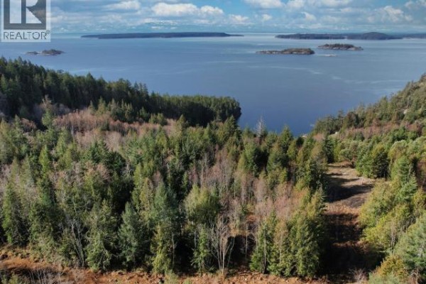Overhead view of forested land sloping towards a wide blue bay with islands on the horizon. - Sl 18 Sarah Point Road, Powell River
