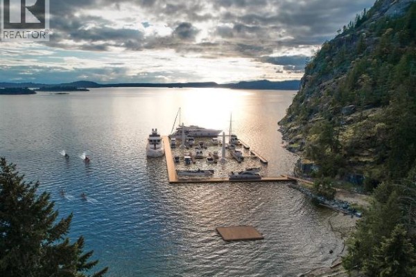 Drone view of a marina with several boats docked, surrounded by water and rocky cliffs. - Sl 27 Sarah Point Road, Powell River