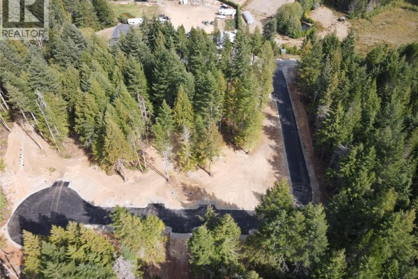 Aerial view of a paved road curving through a forest with nearby houses and RVs. - Sl6 Essex Way, Qualicum Beach