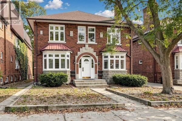 Close-up front exterior view of a red brick multi-family home with arched entryway and stone accents. - South 2nd - 163 Highbourne Road, Toronto