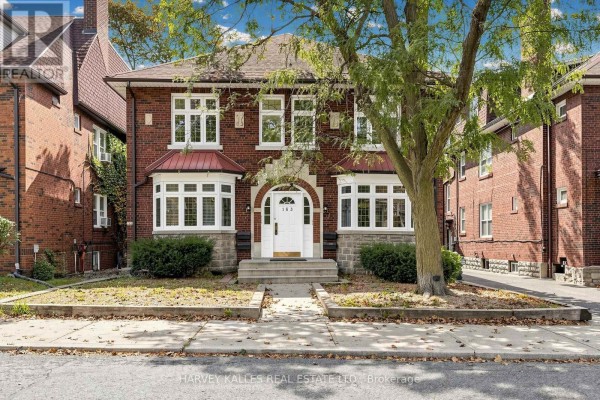 Daylight exterior shot of a red brick multi-family home with a paved walkway and green landscaping. - South 2nd - 163 Highbourne Road, Toronto